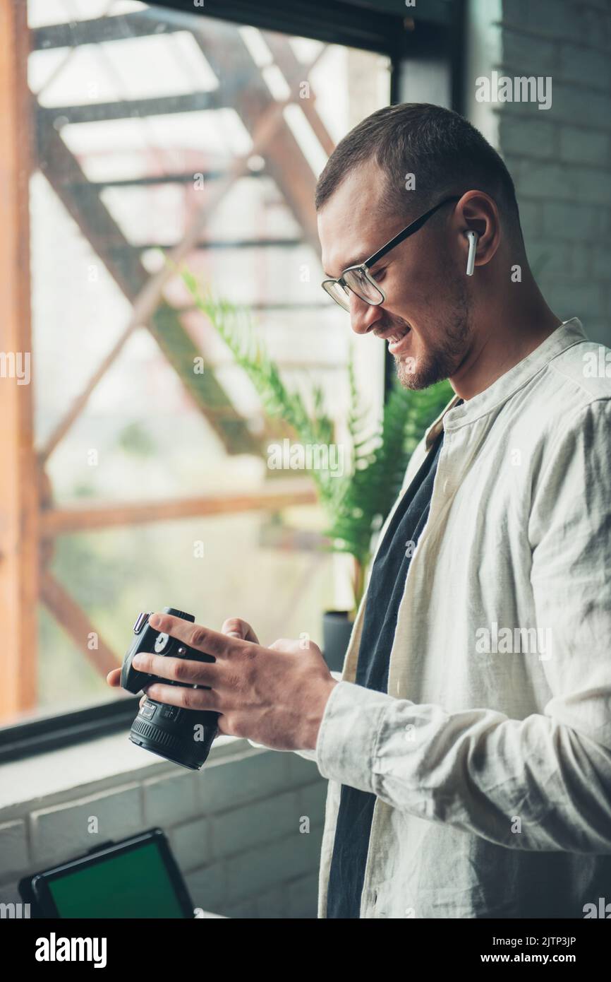 Vue latérale d'un homme tenant un appareil photo en choisissant des photos d'une prise de vue récente. Concept d'entreprise. Technologie de transfert de données. Portrait d'entreprise. Internet Banque D'Images