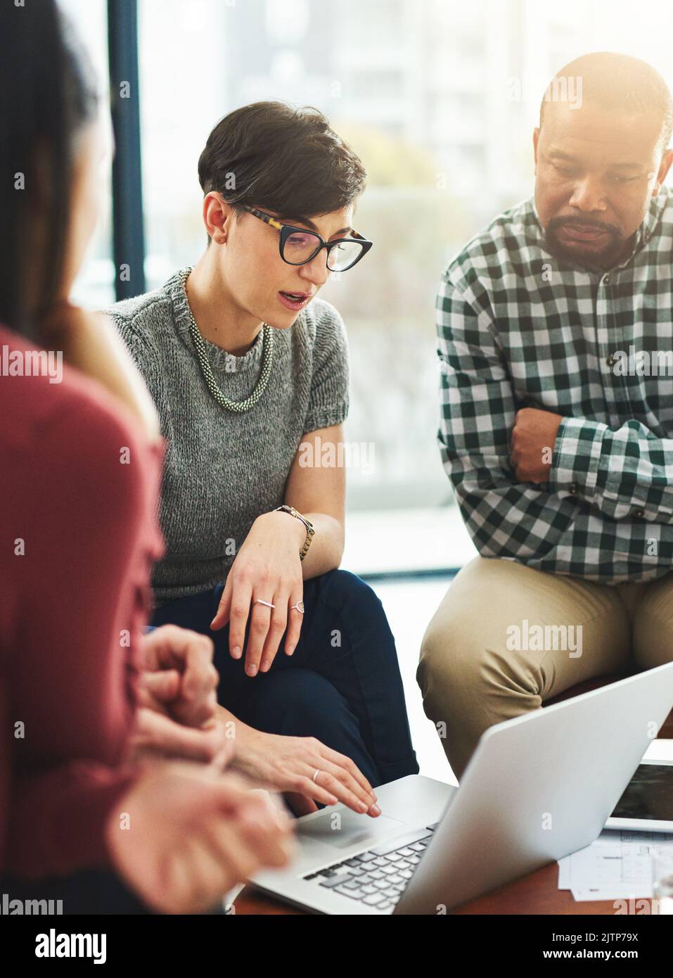Résoudre les problèmes grâce à une meilleure technologie. Un groupe de collègues travaillant ensemble sur un ordinateur portable. Banque D'Images