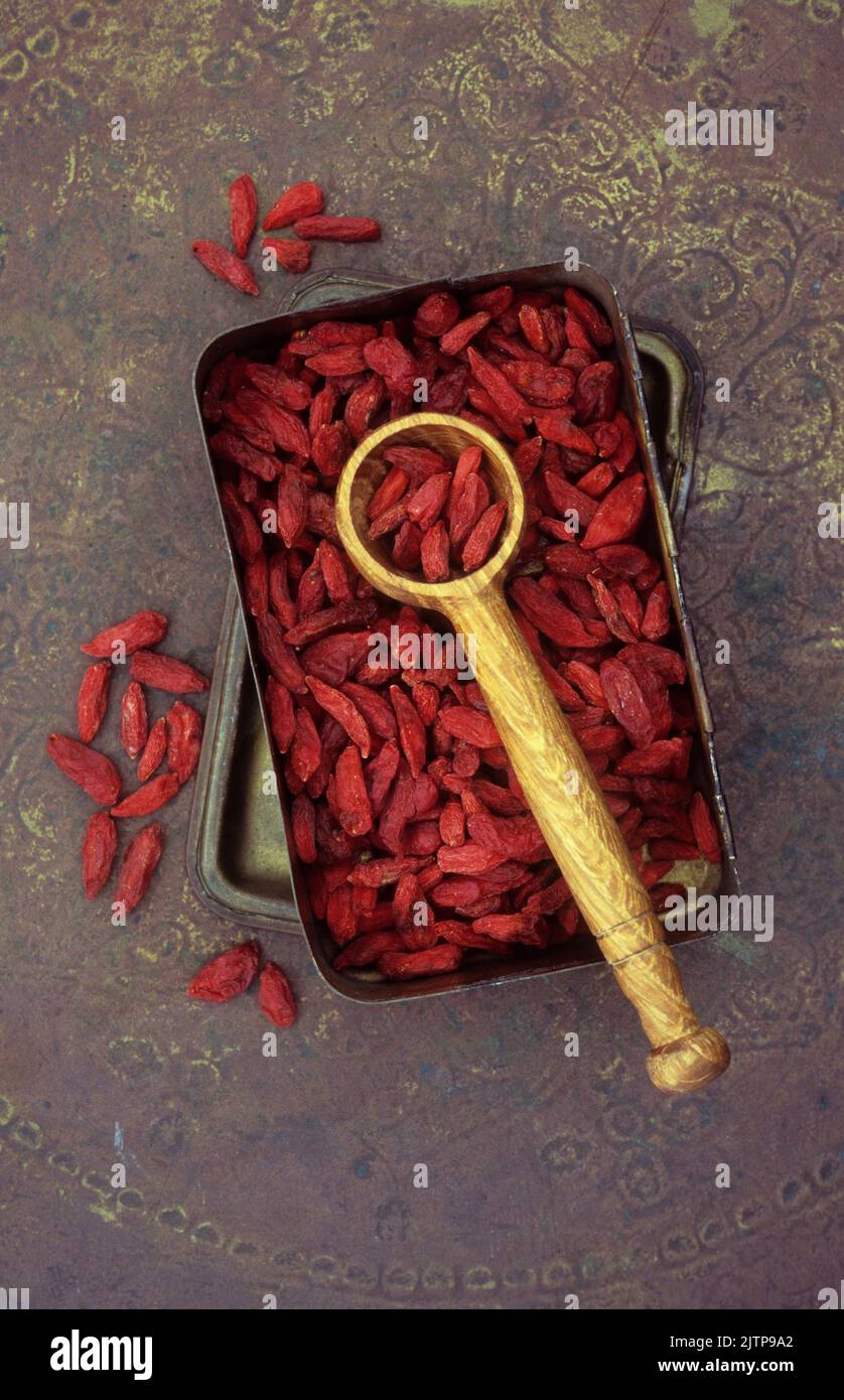 Boîte contenant des baies de goji séchées rouges et une pelle en bois couchée dessus Banque D'Images Boîte contenant des baies de goji séchées rouges et une pelle en bois couchée dessus Banque D'Images