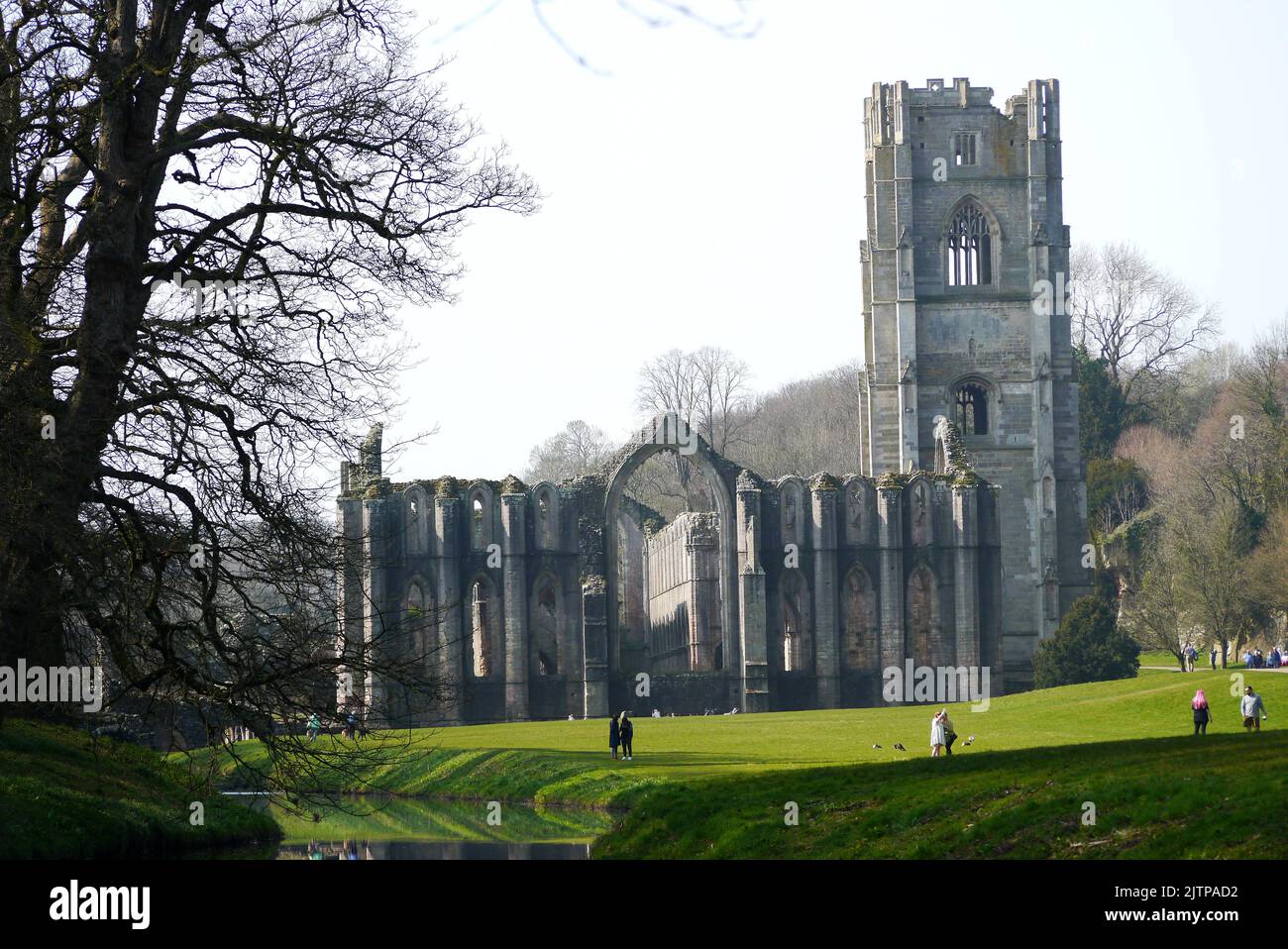 Personnes marchant au bord de la rivière Skell dans le domaine des Fontaines Abbey Cistercien Monastère, North Yorkshire, Angleterre, Royaume-Uni. Banque D'Images