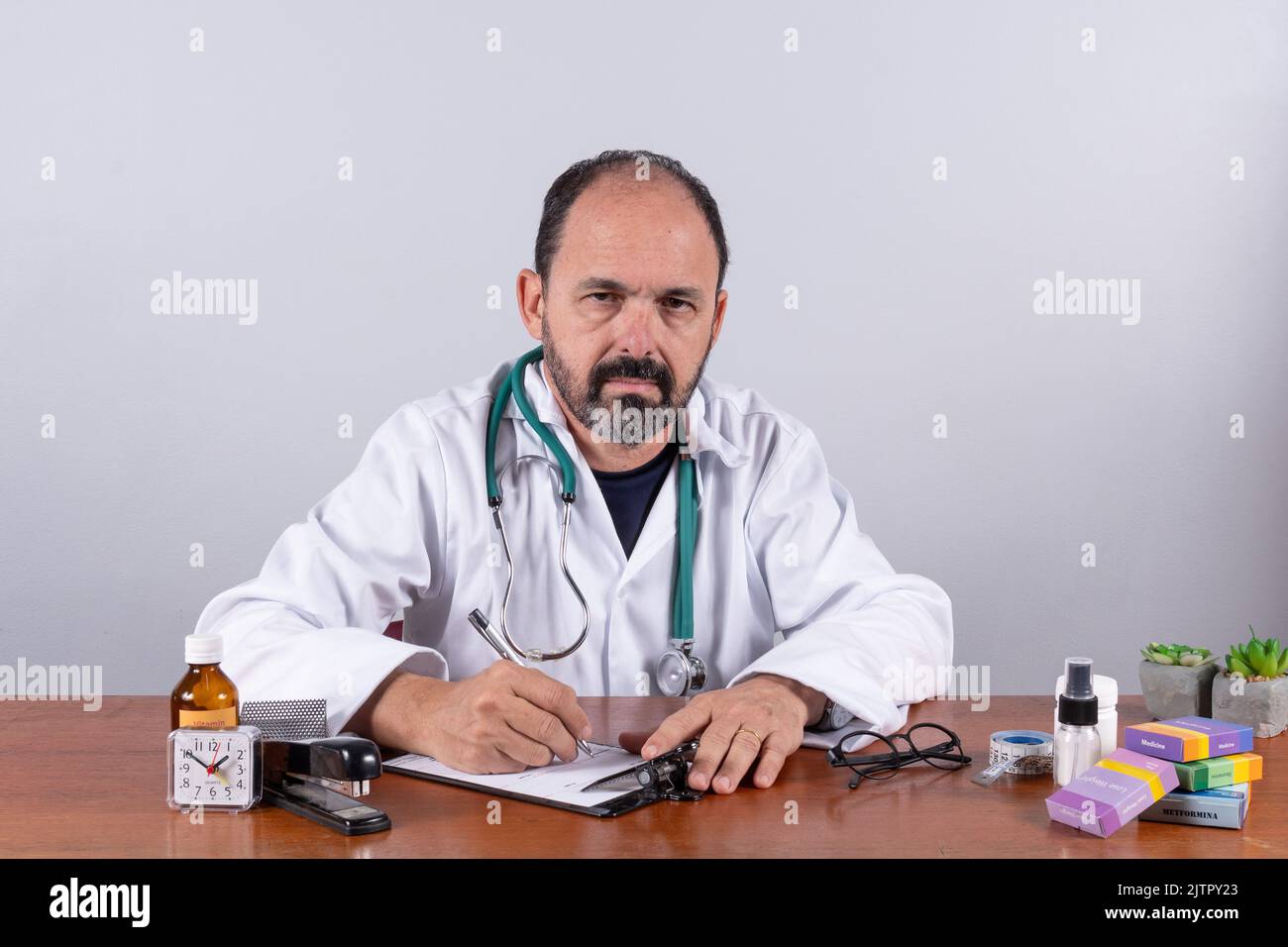 Portrait d'un médecin expérimenté mature écrivant sur ordonnance et regardant l'appareil photo Banque D'Images