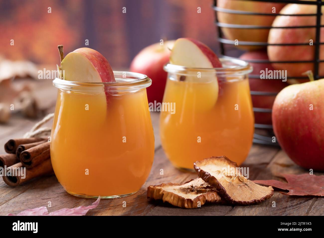 Verre de cidre de pomme avec tranches de pomme sur table en bois et fond d'automne Banque D'Images