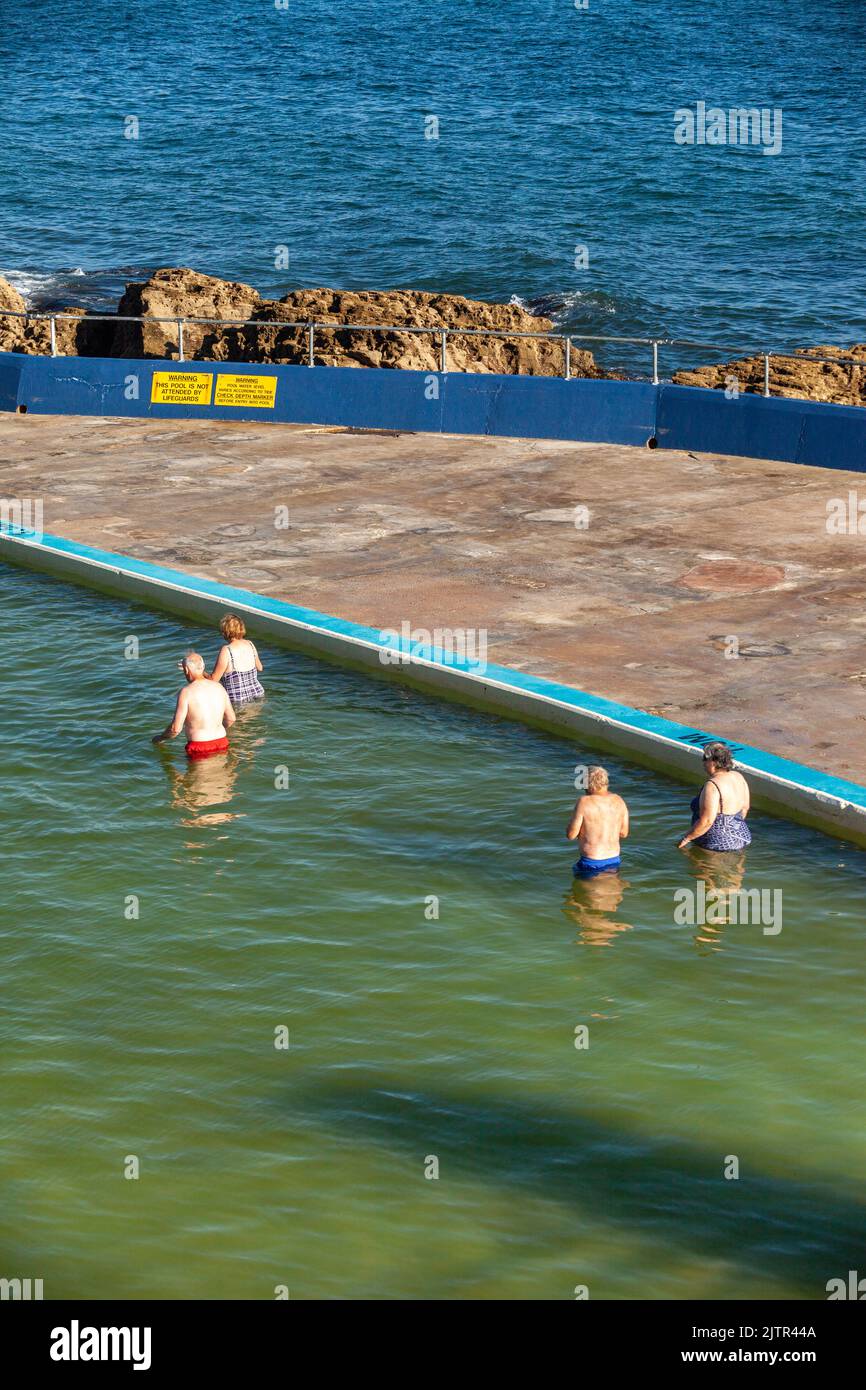 Quatre personnes marchant dans une piscine en plein air à Brixham. Banque D'Images