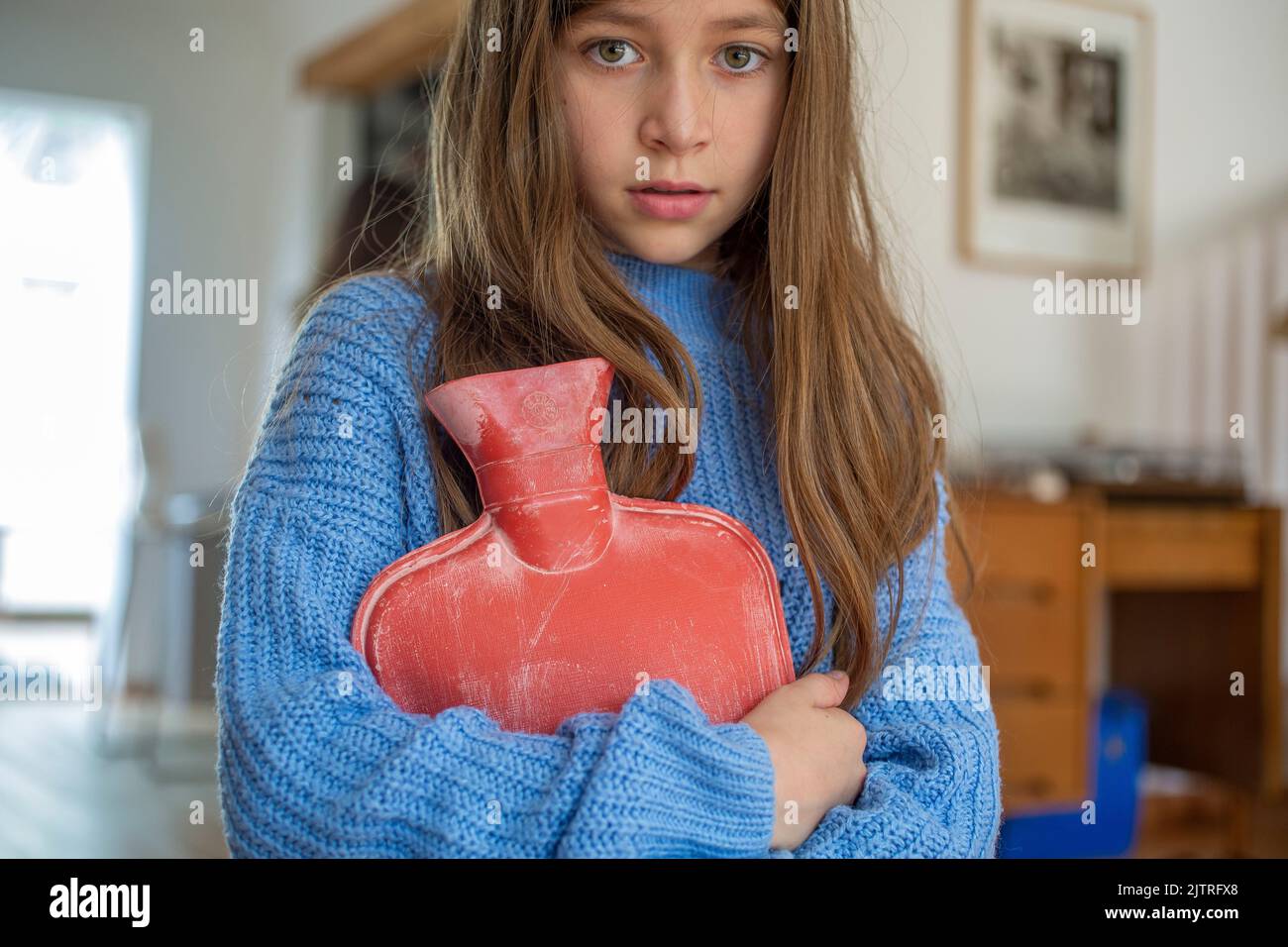 petite fille tenant une bouteille d'eau chaude contre elle. Banque D'Images