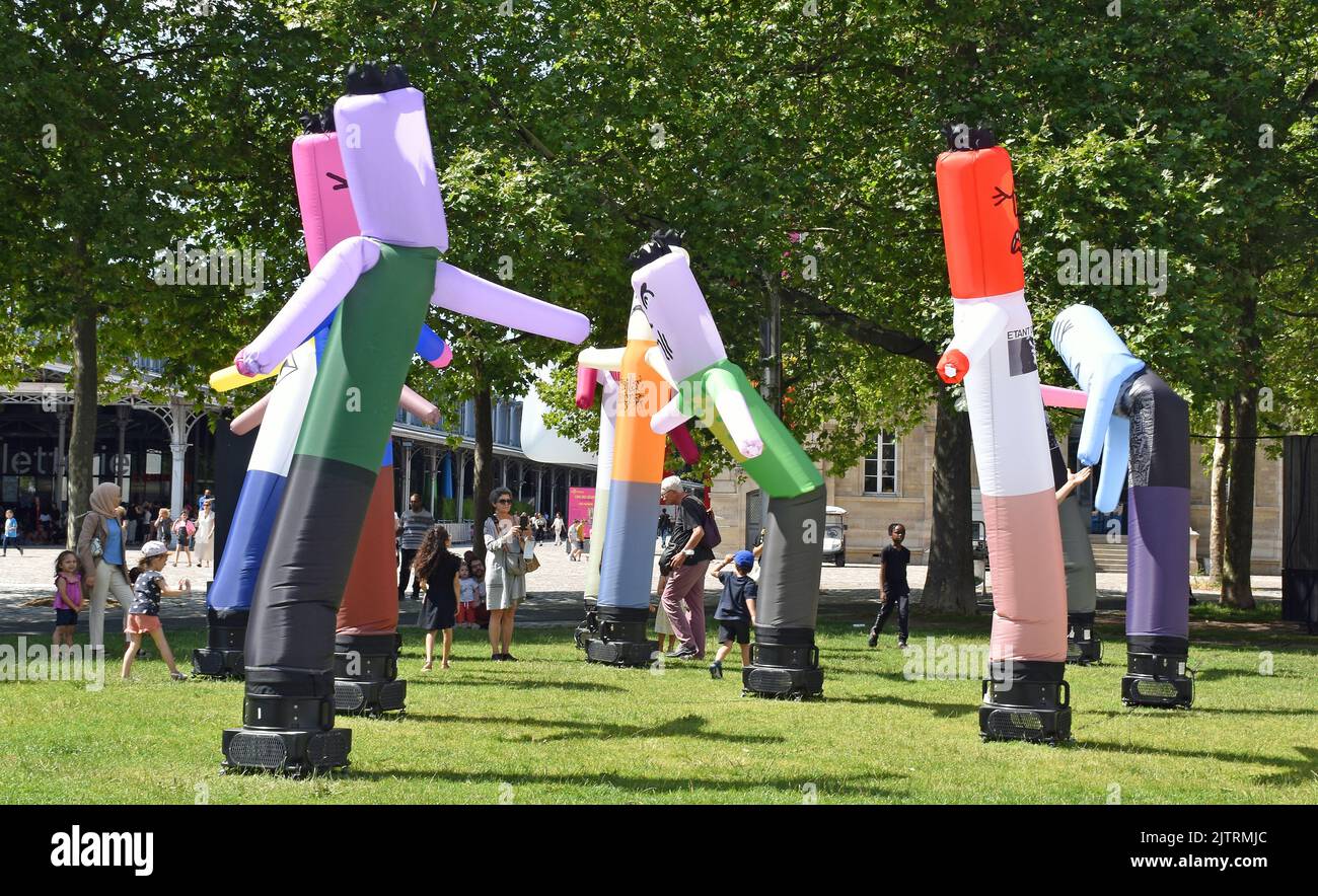 Les petits enfants, regardés par leurs parents, jouent avec de grands personnages de dessins animés gonflables fins qui peuvent être poinçonnés, puis rebondissent en arrière. Banque D'Images