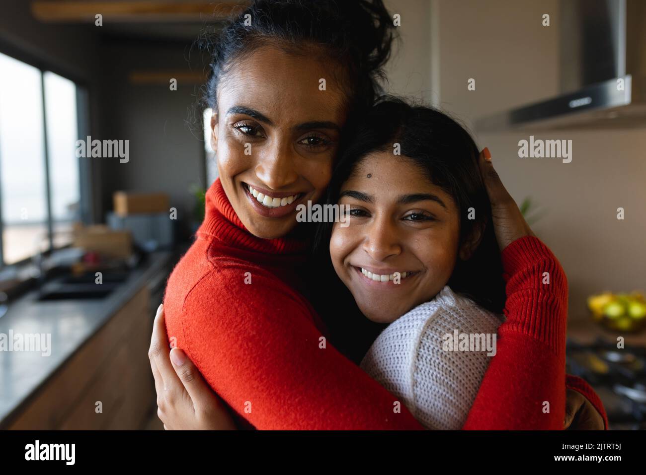 Portrait en gros plan de la mère et de la fille biraciales souriantes qui s'embrasse dans la cuisine à la maison, espace de copie Banque D'Images