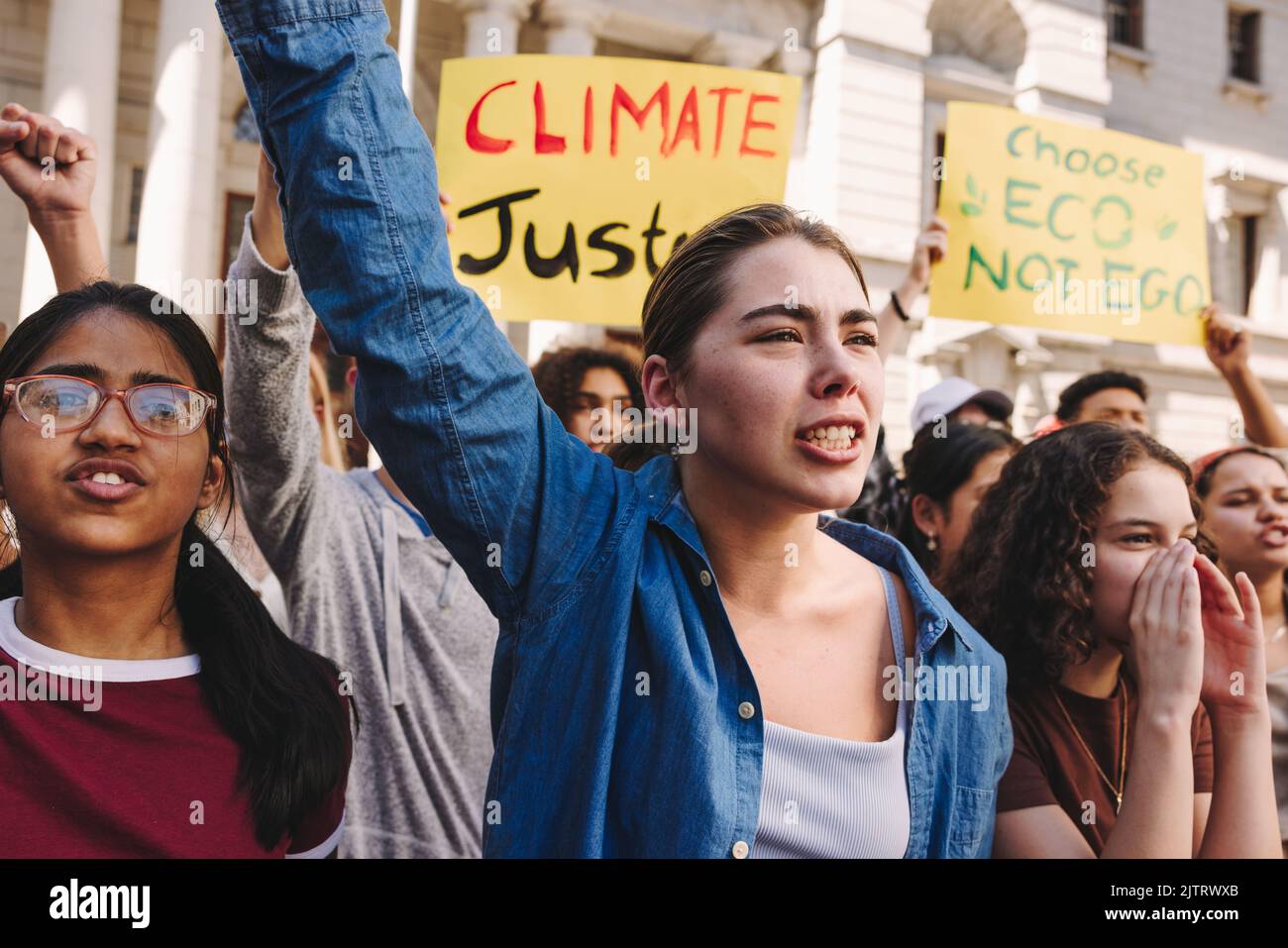 Des jeunes activistes dynamiques élèvent des affiches et crient des slogans lors d'une manifestation contre le changement climatique. Groupe de jeunes multiculturels marchant pour le climat Banque D'Images