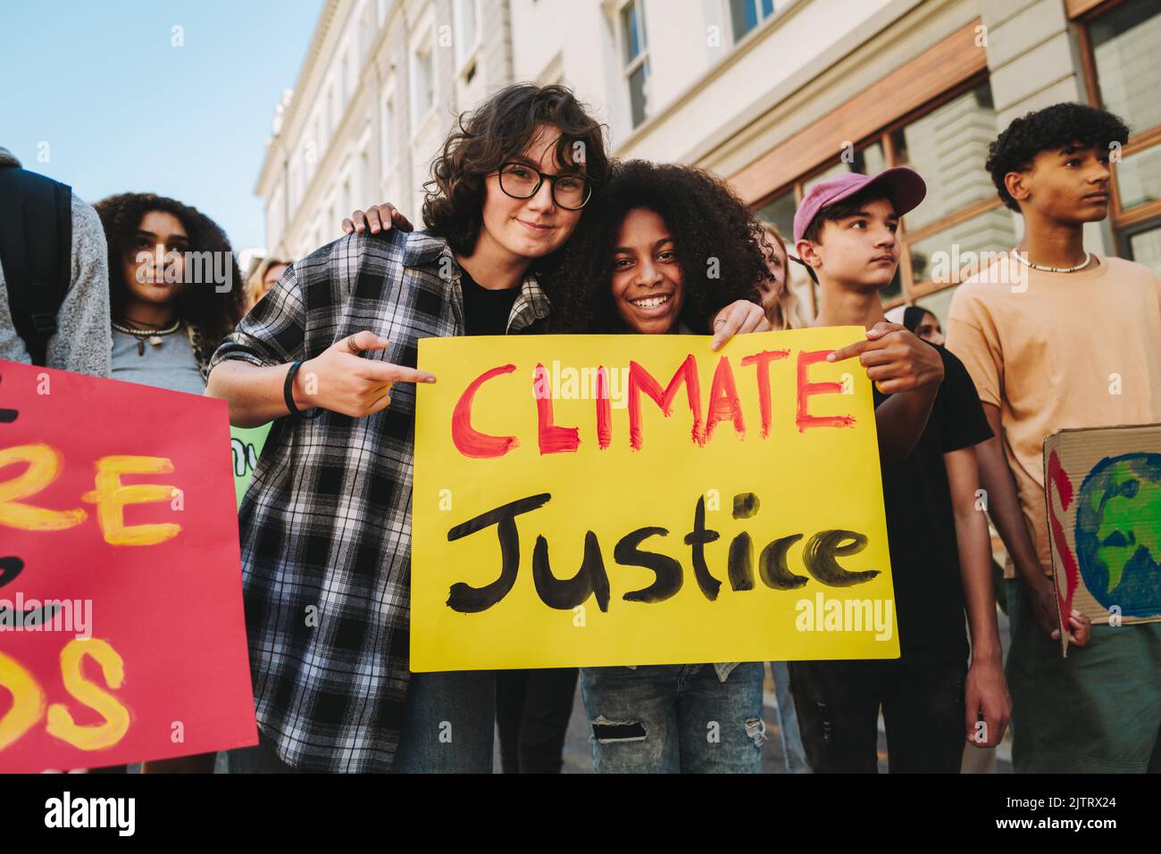 Des adolescentes heureuses tenant une affiche lors d'une marche sur le changement climatique. Groupe de jeunes militants multiculturels protestant contre le réchauffement climatique. Divers youn Banque D'Images