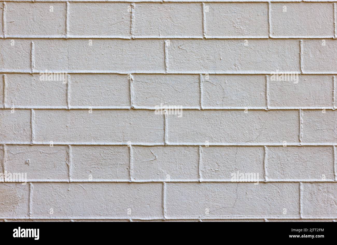 L'ancien mur de brique est complètement enduit de mortier beige avec joints de ciment exposés. Banque D'Images