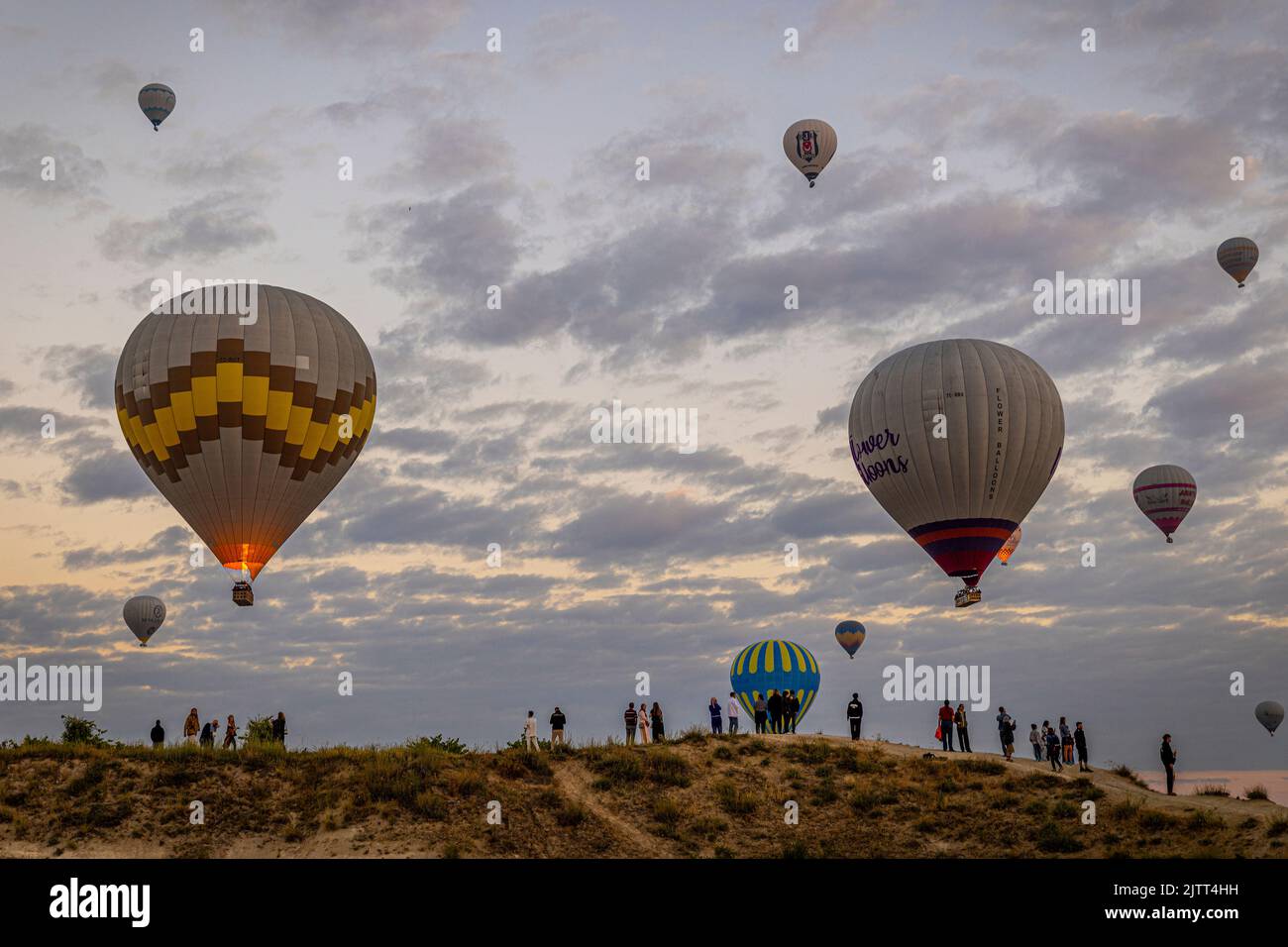 GÖREME/TURQUIE - 30 juin 2022: Les touristes regardent le spectacle de montgolfière au-dessus de göreme à l'aube Banque D'Images