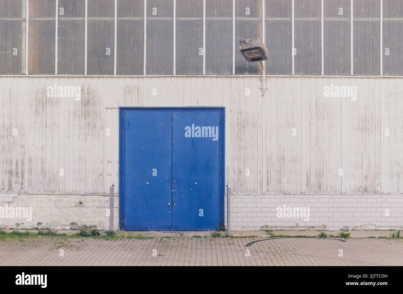 Façade d'un bâtiment d'usine avec porte bleue et éclairage Banque D'Images
