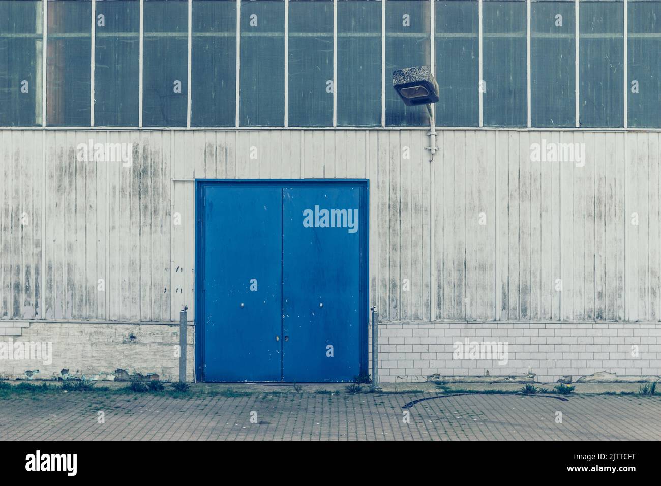 Façade d'un bâtiment d'usine avec porte bleue et éclairage Banque D'Images