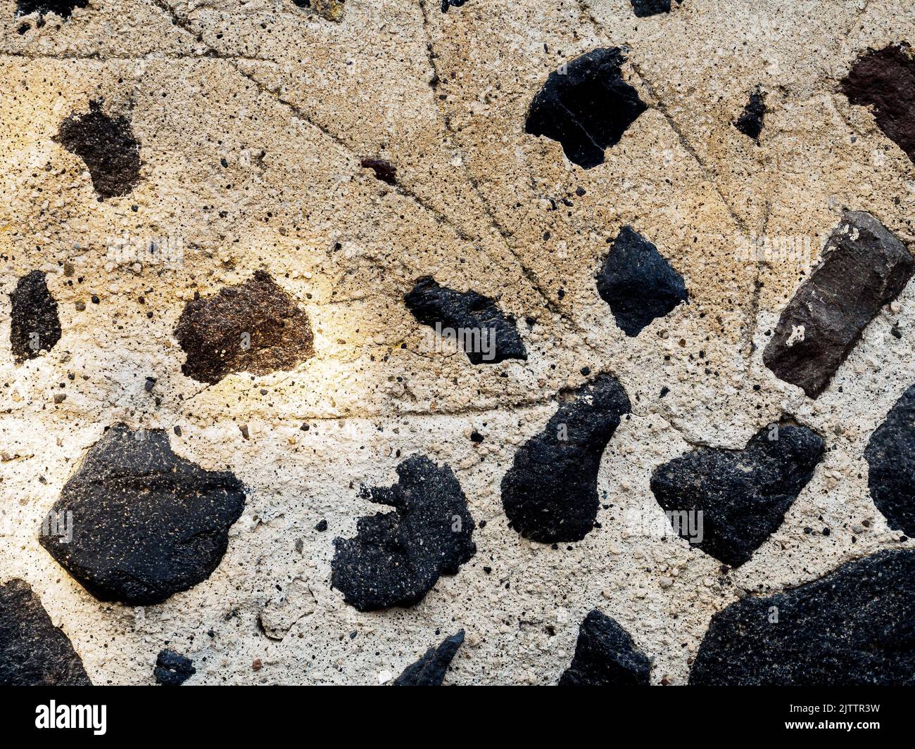 Mur en plâtré beige avec pierres noires Banque D'Images