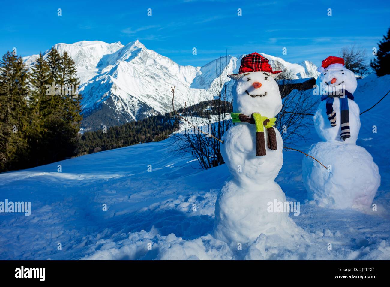 Deux bonhommes de neige construisent avec un chapeau de carotte et un foulard sur les montagnes Banque D'Images