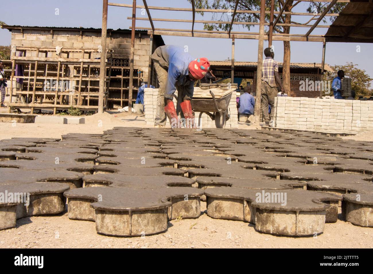 Un homme est vu poser des pavés pour sécher à Lilongwe. Les finisseurs sont fabriqués à la main à partir de ciment et de sable. Malawi. Banque D'Images