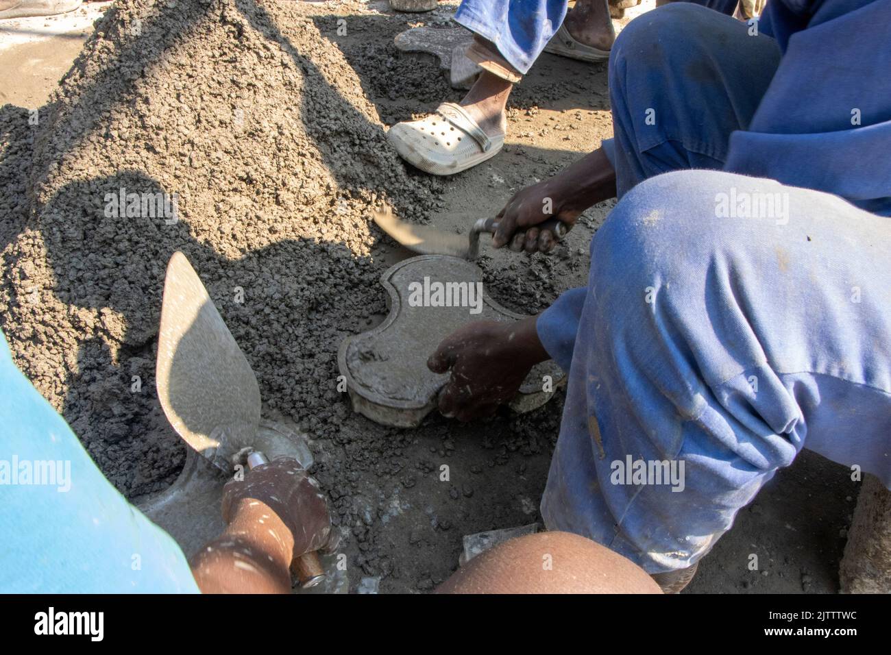 On voit des hommes fabriquer des briques de pavage à la main dans un lieu de fabrication local de la zone 49 Habitat, à Lilongwe, au Malawi. Banque D'Images