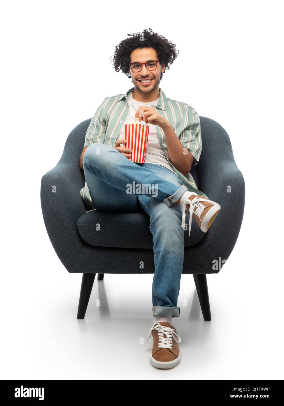 jeune homme souriant avec pop-corn assis sur une chaise Banque D'Images