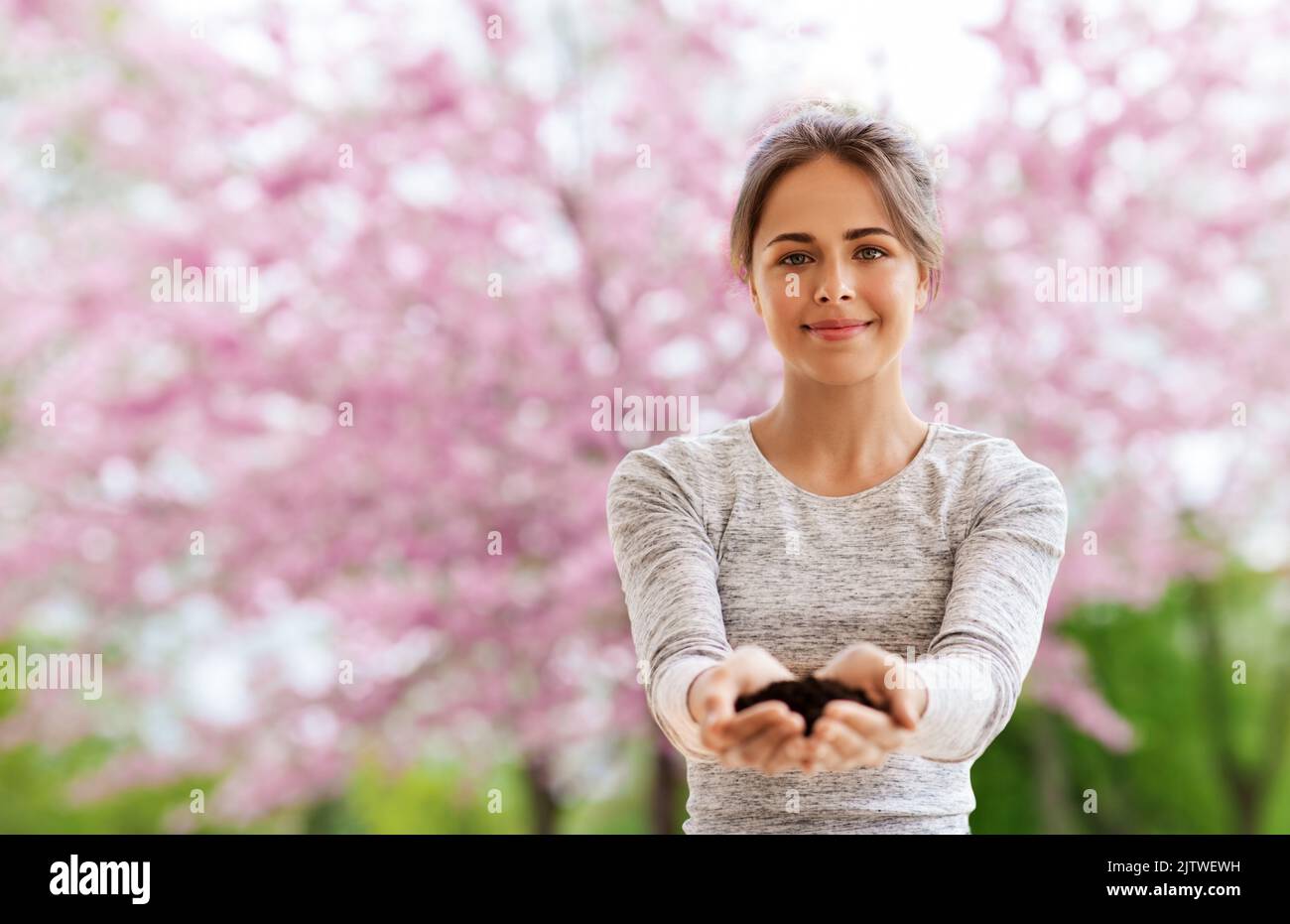 femme avec une poignée de terre dans le jardin de printemps Banque D'Images