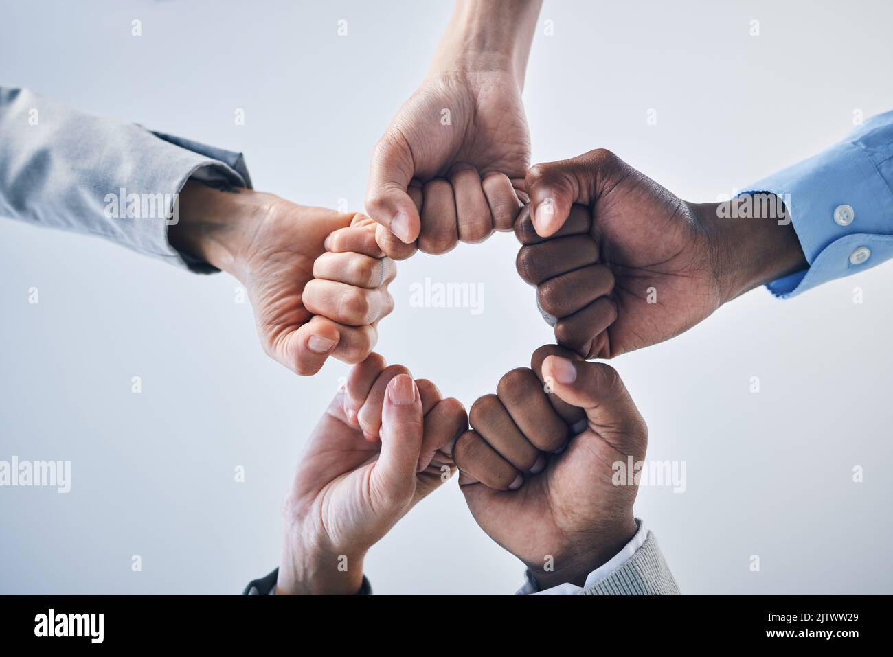 Le travail d'équipe, la motivation et la collaboration s'embuent des mains geste, signe ou icône ci-dessous sur la maquette d'arrière-plan de mur de studio. Groupe de travailleurs de la diversité ou Banque D'Images