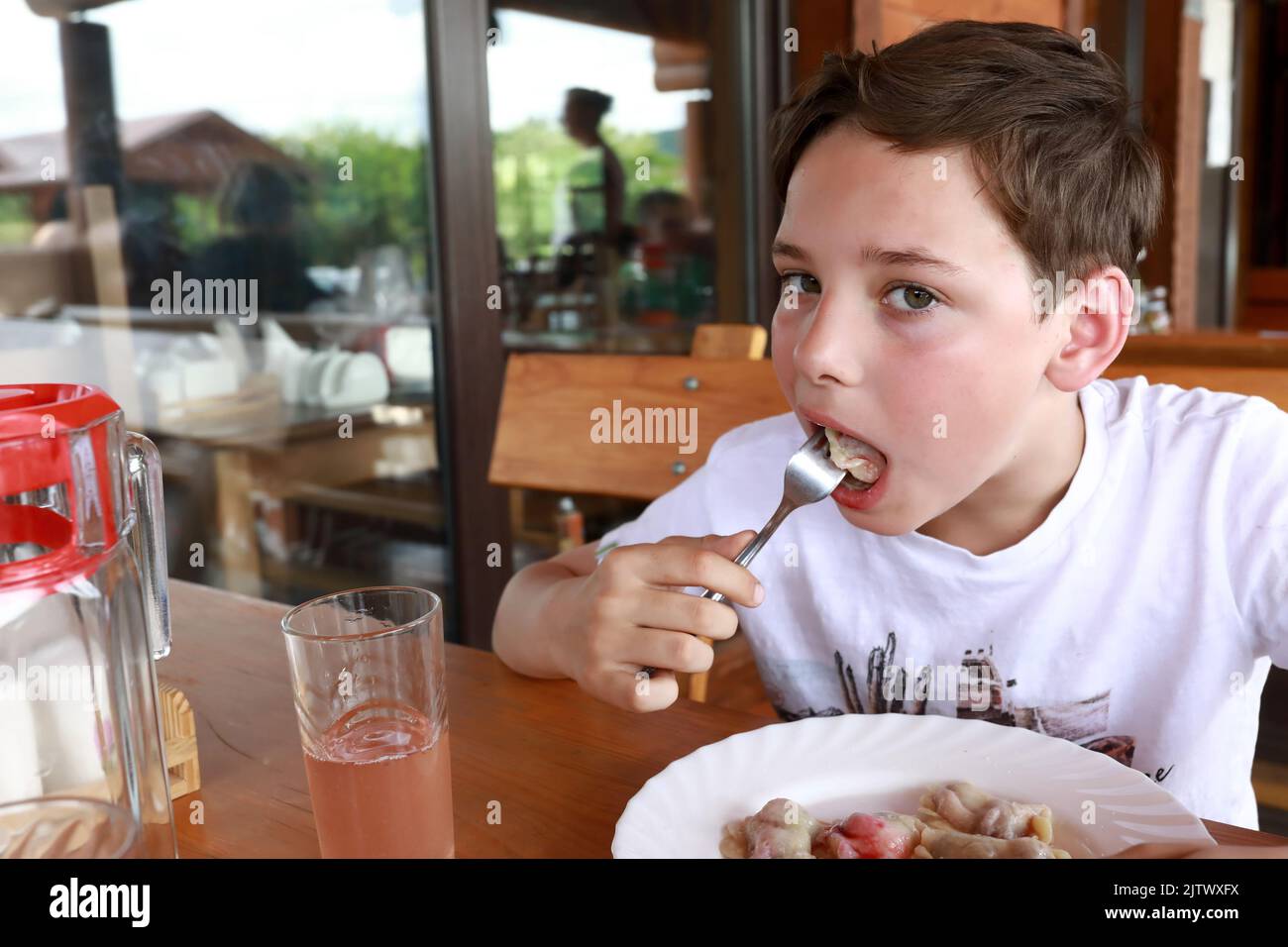 Un enfant mange du varéniki farci de cerises au restaurant Banque D'Images