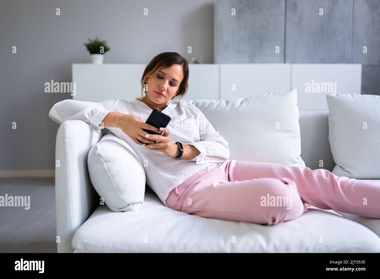 Femme souriante utilisant un smartphone à la maison Banque D'Images