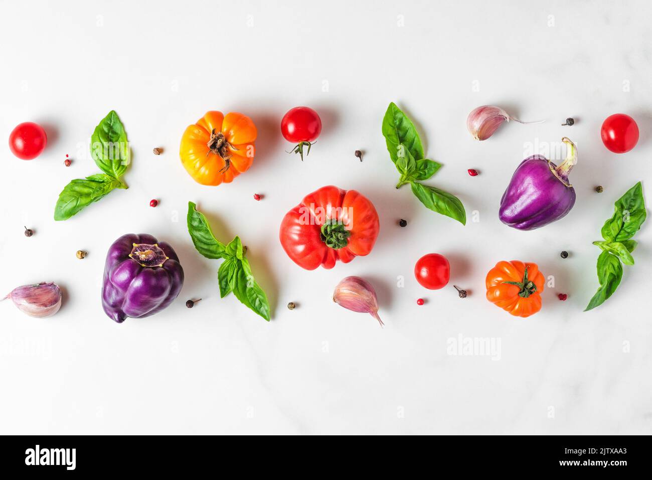 Mise en page créative faite de tomates, de poivre, d'ail, de feuilles de basilic. Pose à plat. Vue de dessus. Composition des aliments. Légumes isolés sur fond blanc. Nourriture dans Banque D'Images