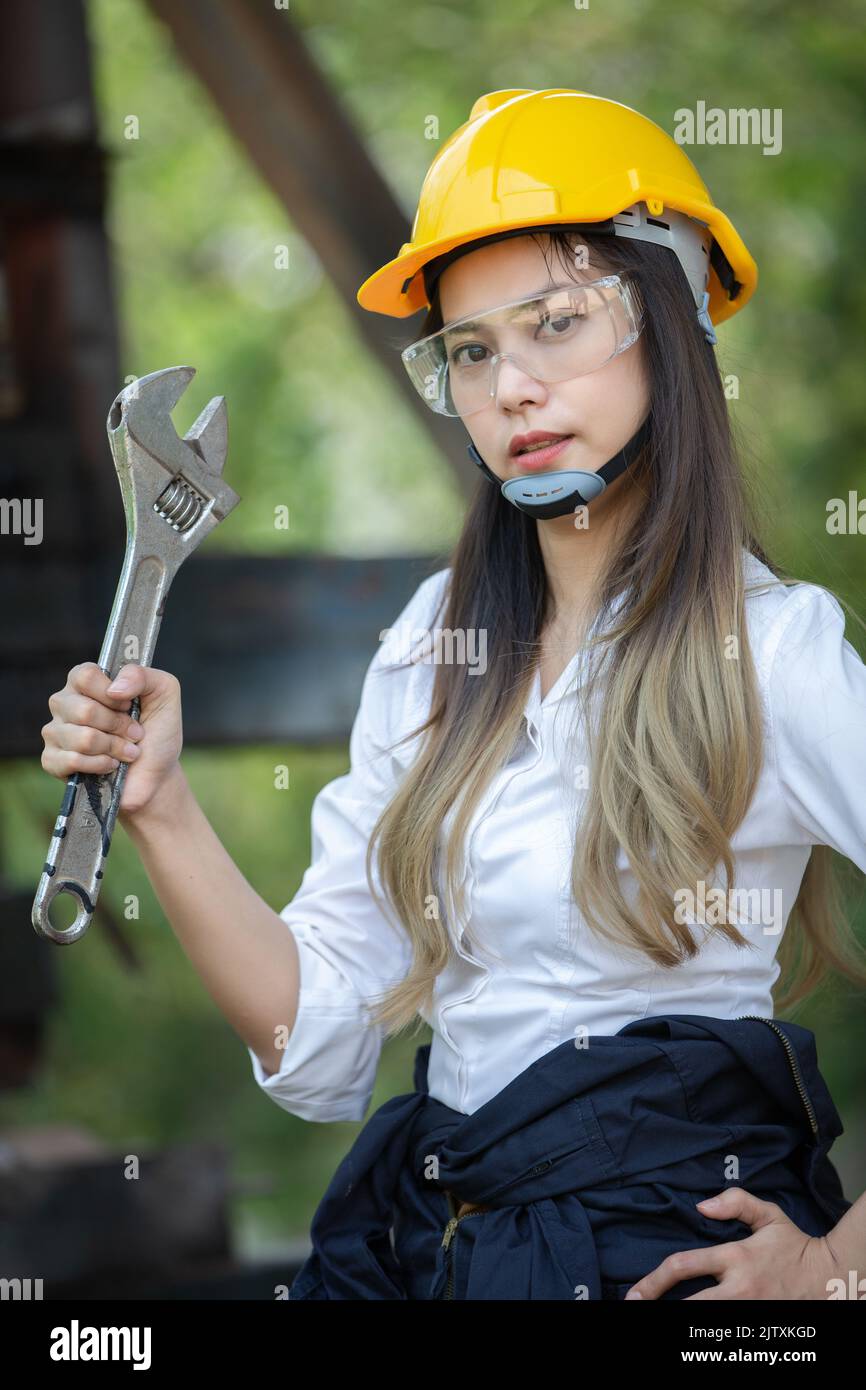Femme ingénieur souriant avec un casque à chapeau rigide jaune et tenant et tenant une clé. Banque D'Images