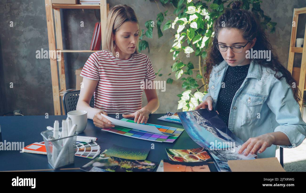 Les créateurs placent des photos colorées sur une table et partagent leurs idées tout en étant assis dans un bureau moderne. Concept de pensée créative. Banque D'Images