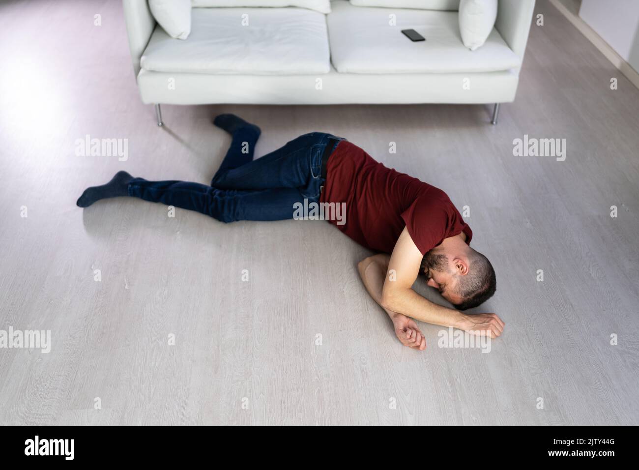 Jeune homme inconscient Lying On Floor In Living Room Banque D'Images
