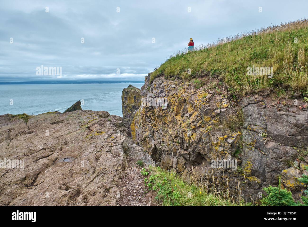 Femelle sur une corniche à 400 pieds au-dessus de la baie de Fundy, à Cape Split, Nouvelle-Écosse, prenant une photo avec son téléphone portable. Banque D'Images