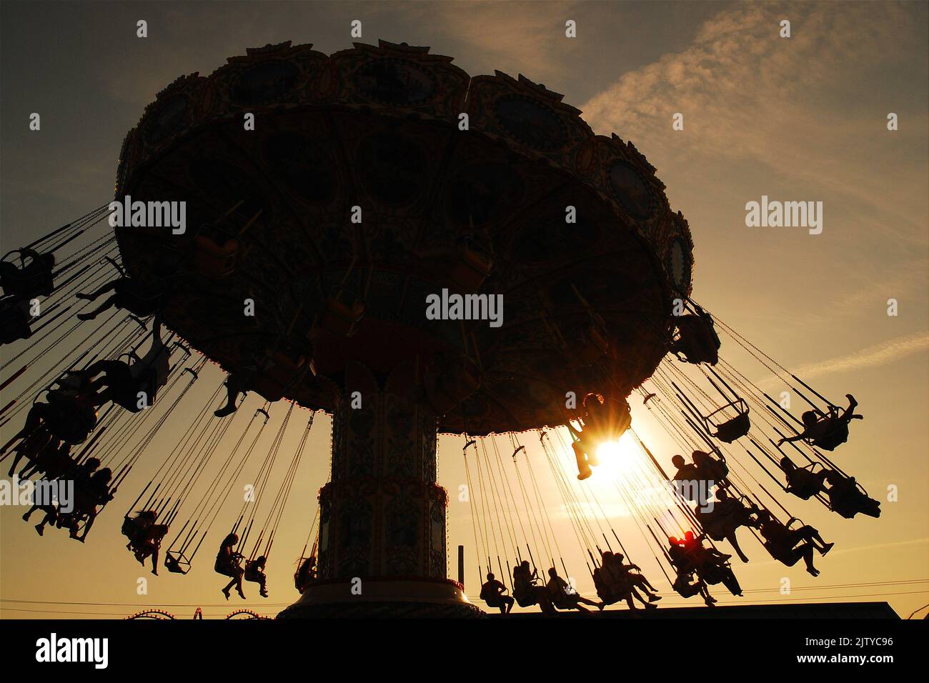 Les amateurs de sensations fortes glissent dans les airs au coucher du soleil lors d'une excursion d'swing le jour de vacances d'été Banque D'Images