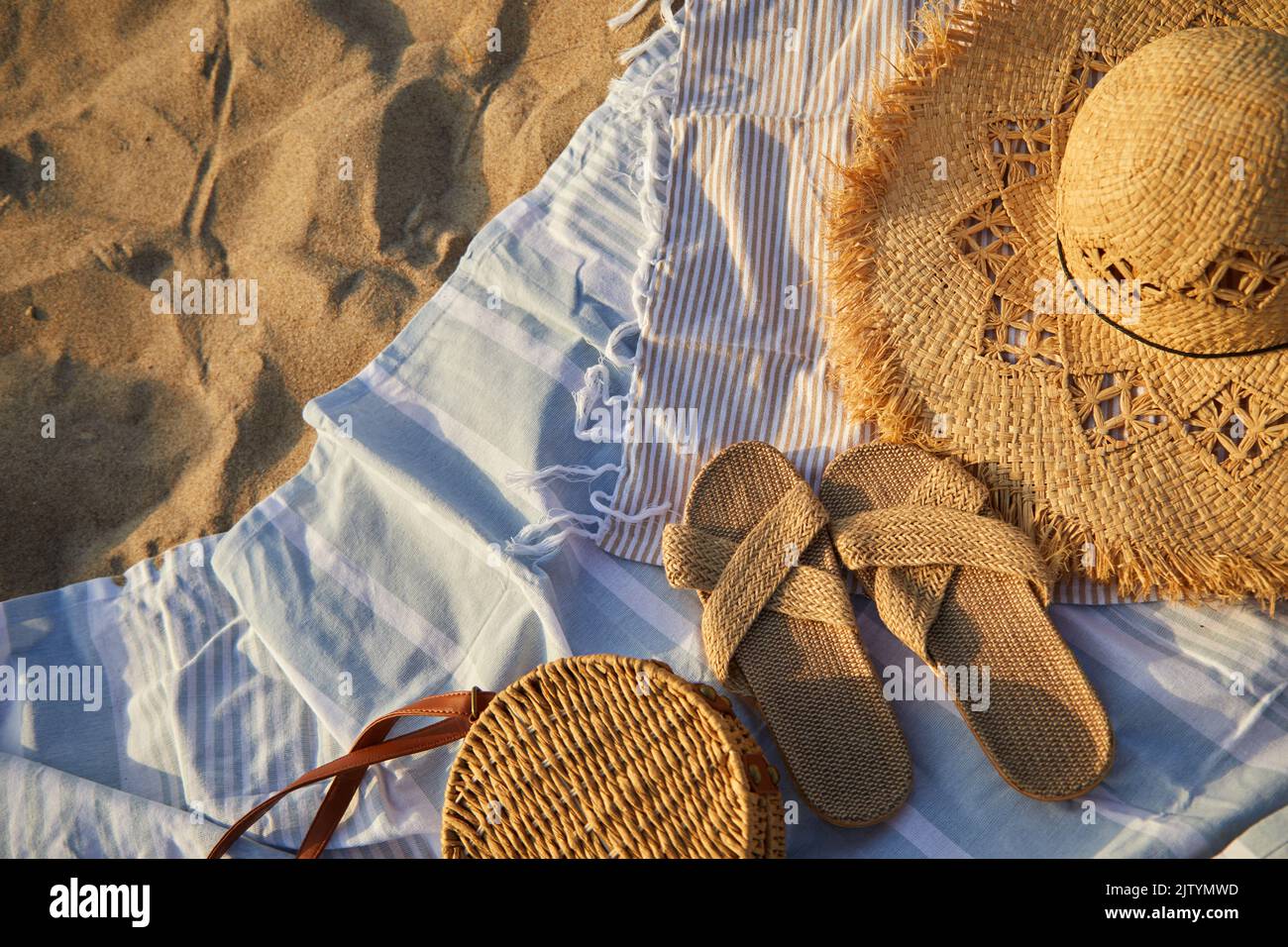 Vue de dessus des accessoires de plage. Chapeau de paille, sac, tongs sur sable à la plage. Banque D'Images
