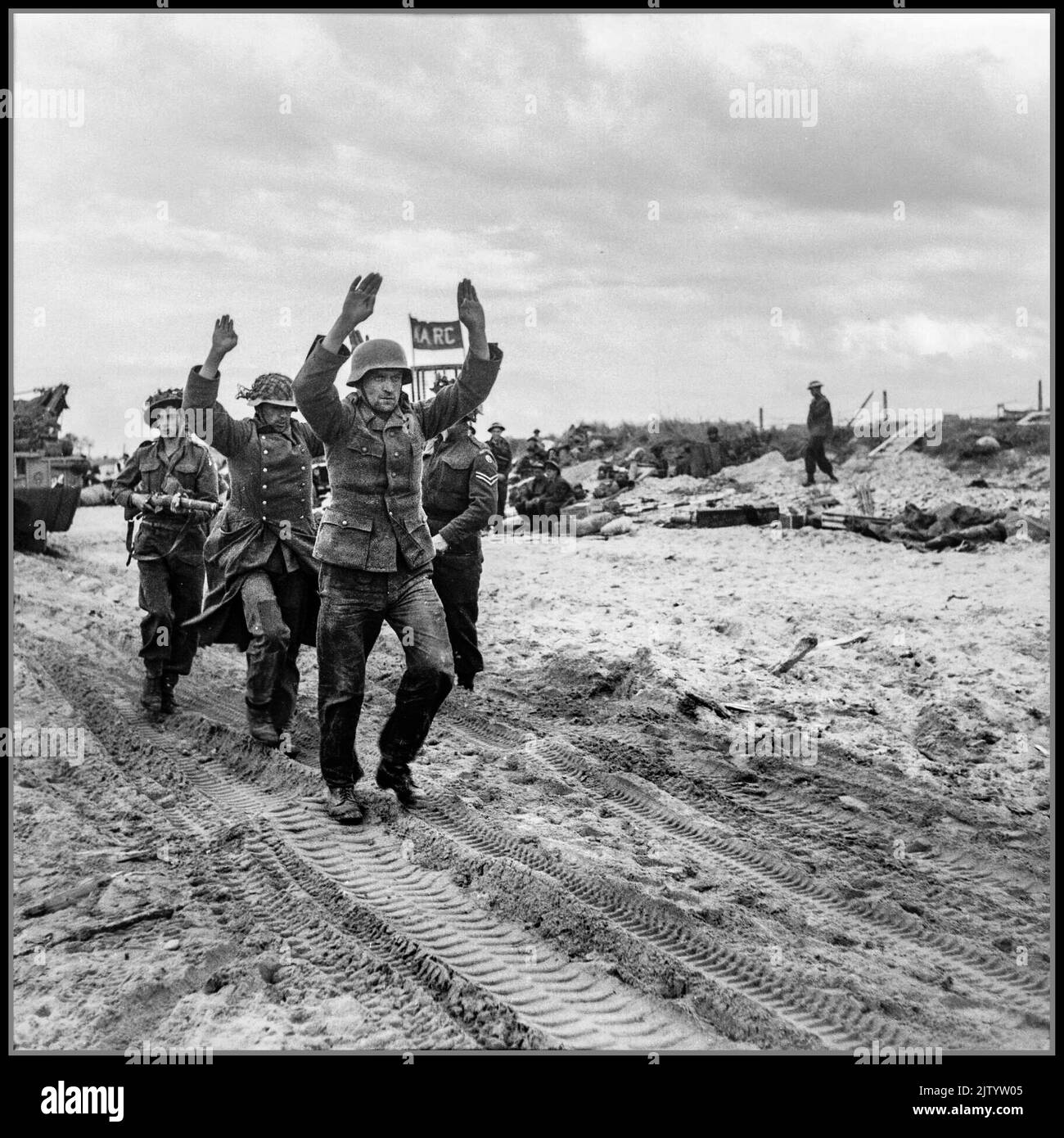 WW2 jour J - capturé prisonniers de guerre allemands nazis par les forces armées britanniques pendant l'invasion de la Normandie 6 juin 1944 la Wehrmacht était les forces armées unifiées de l'Allemagne nazie de 1935 à 1945. Les prisonniers de guerre allemands, avec les mains levées, sont escortés le long de l'une des plages de la région de l'or, 6 juin 1944. Normandie France Banque D'Images