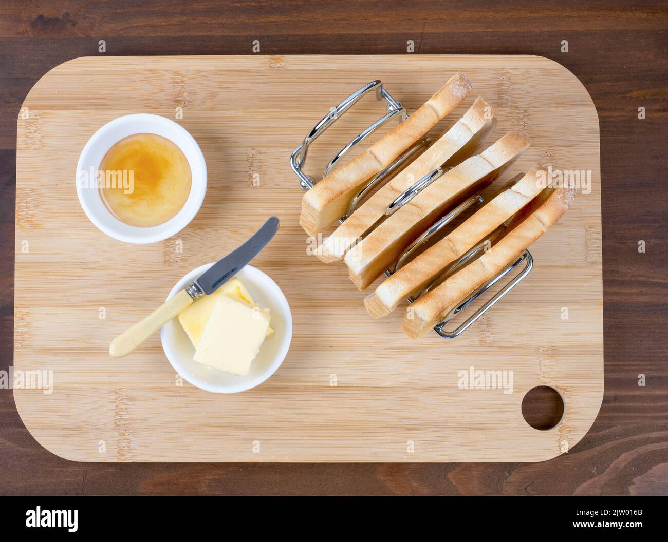 Plat Lay grille porte-pain rempli de couteau à beurre toast et marmelade sur un fond en bois Banque D'Images