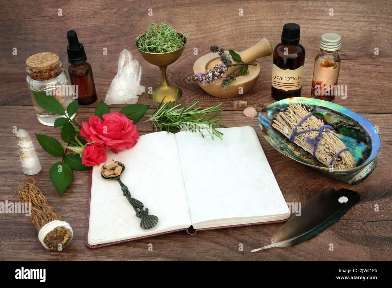 Matériel de cérémonie de purification et ingrédients de potion d'amour pour le sort magique avec bloc-notes, herbes, fleurs de rose, huile et cristaux. Banque D'Images