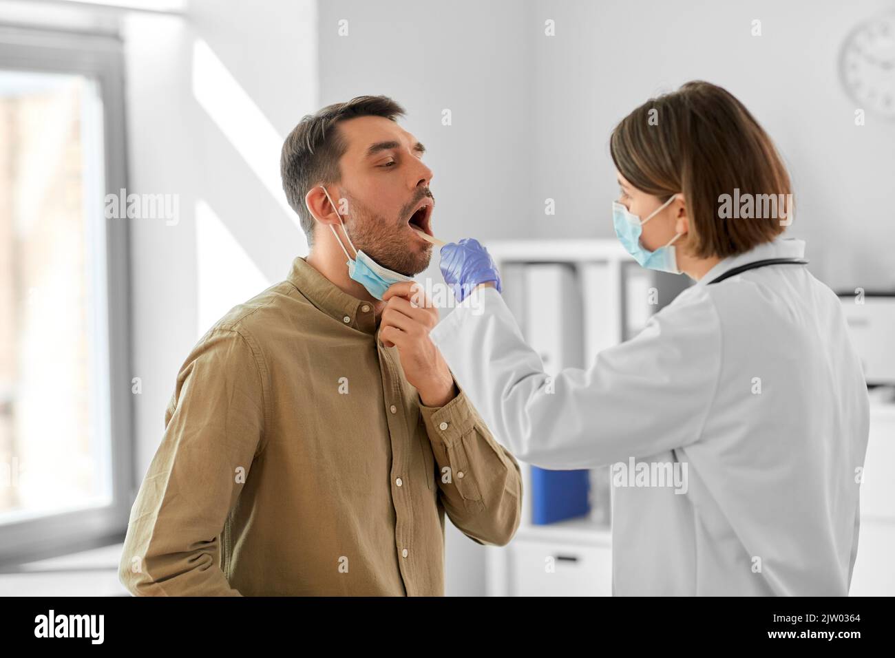 médecin vérifiant la gorge du patient mâle à l'hôpital Banque D'Images