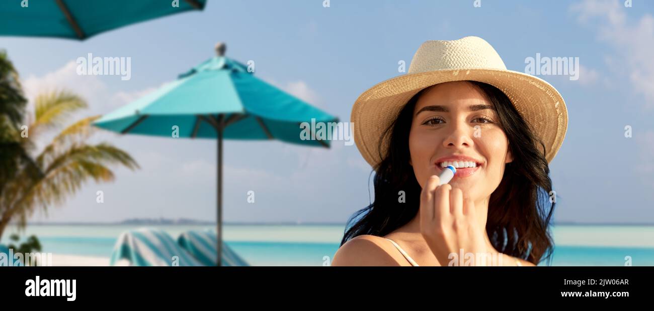 femme souriante en bikini avec baume à lèvres sur la plage Banque D'Images