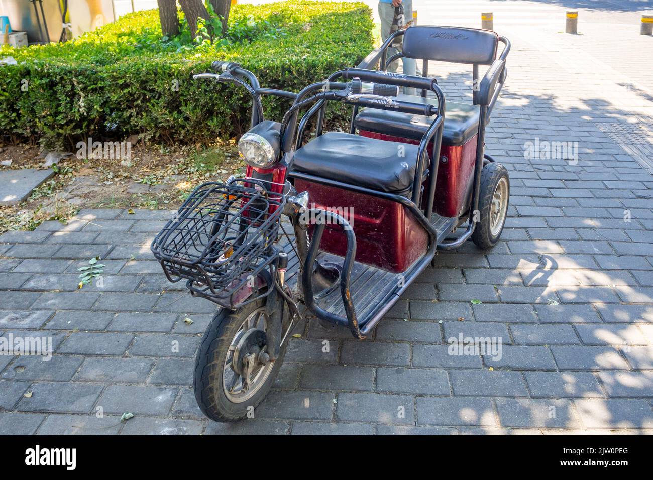 Un tricycle à deux places est stationné dans un trottoir dans le quartier du centre-ville. Banque D'Images