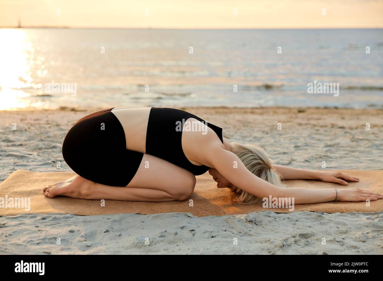 femme faisant yoga enfant pose sur la plage Banque D'Images
