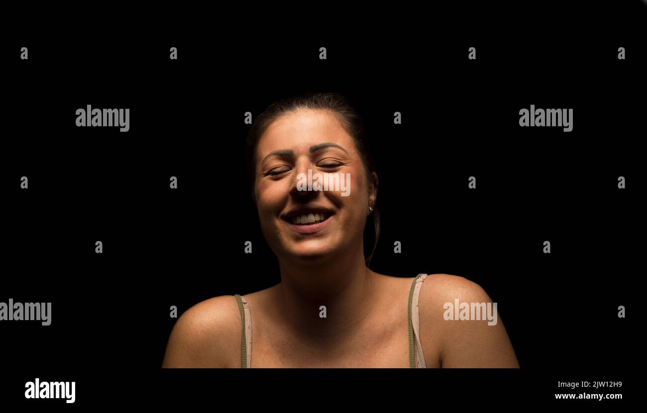 Une femme caucasienne riant avec ses yeux fermés. Banque D'Images