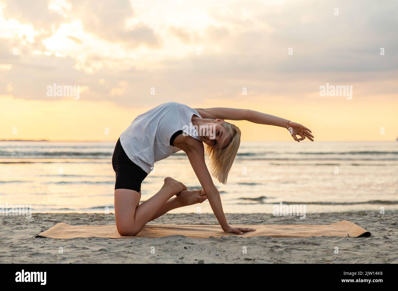 femme faisant du yoga pose de chameau sur la plage Banque D'Images