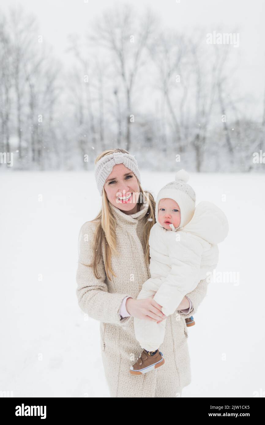 La mère blonde, de race blanche, tient le bébé dans la neige. Banque D'Images