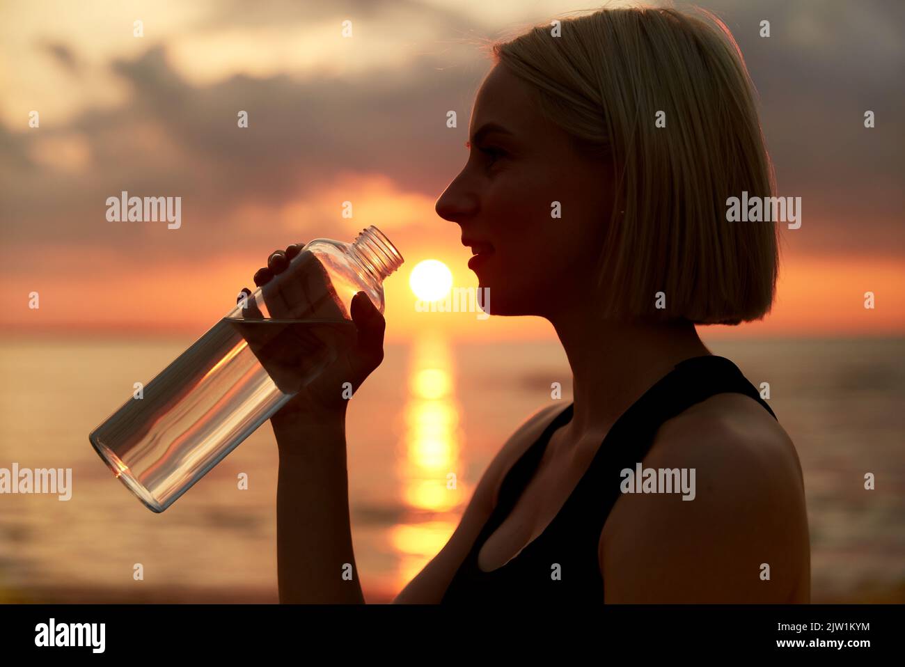 femme buvant de l'eau à la bouteille sur la plage Banque D'Images