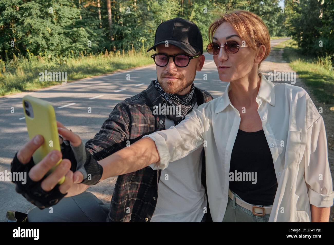 Couple d'âge moyen à bord d'une moto s'amusant et prenant un selfie sur un appareil photo de téléphone portable Banque D'Images