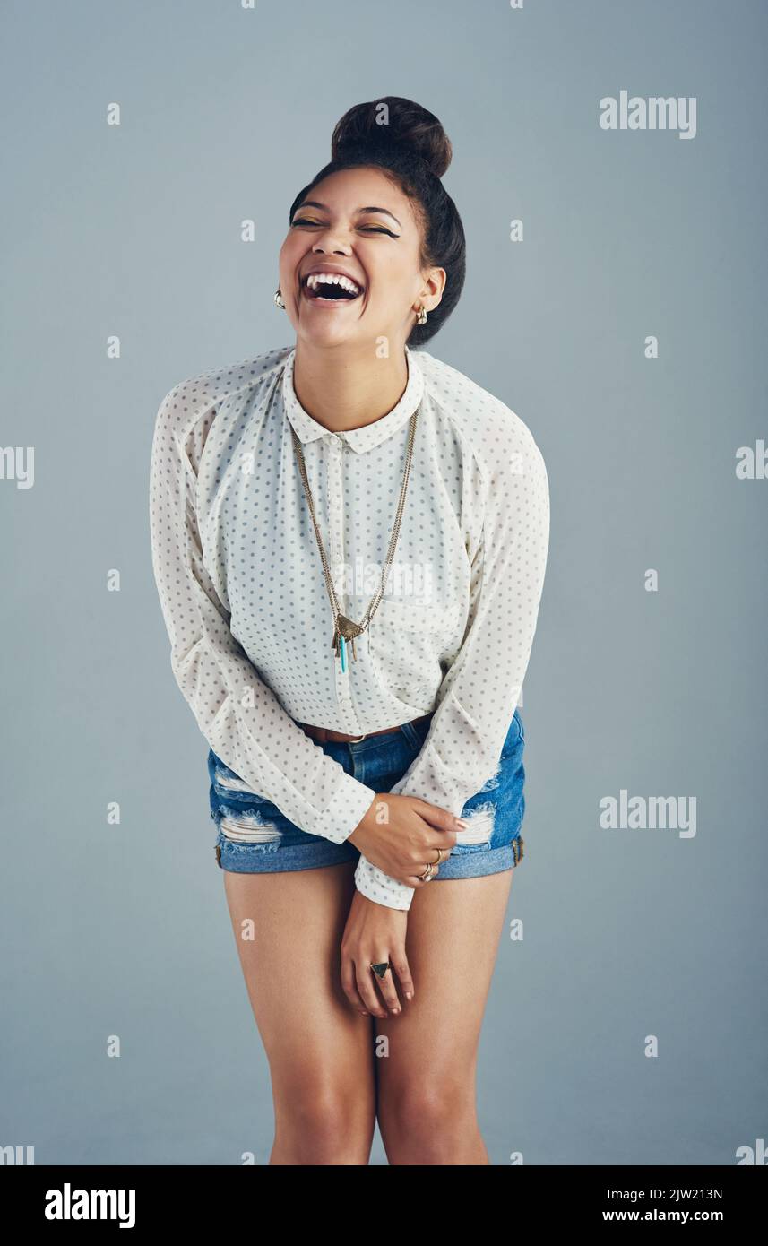 Rire hystériquement. Photo en studio d'une jeune femme attrayante qui rit sur fond gris. Banque D'Images