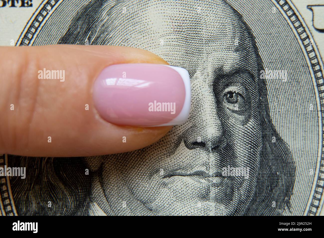Le doigt d'une femme se trouve sur cent dollars et ferme l'oeil à Benjamin Franklin, la finance et l'économie, la main d'une femme sur l'argent Banque D'Images