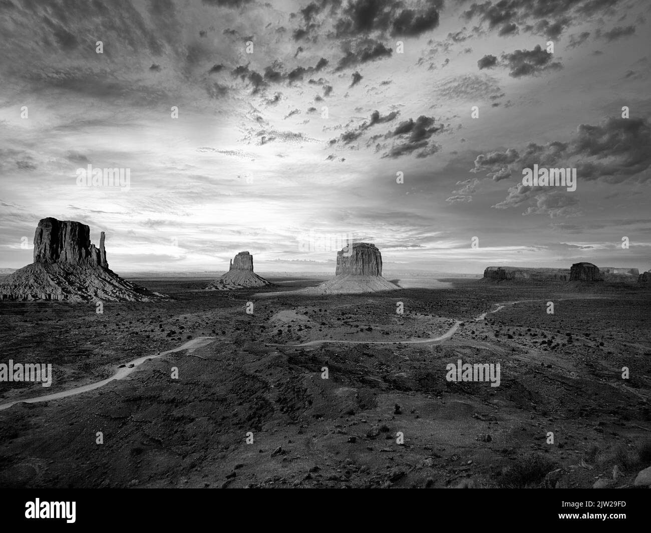 Route panoramique, route de gravier dans Monument Valley, roches proéminentes, West Mitten Butte, East Mitten Butte, Merrick Butte à l'horizon, crépuscule Banque D'Images