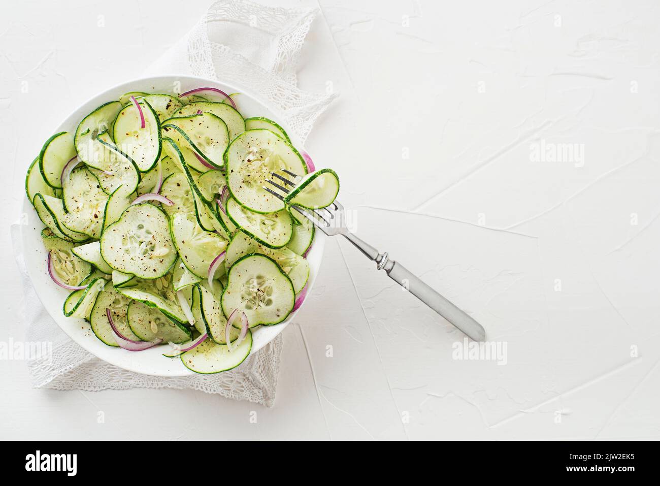 Salade de concombre avec oignon et vinaigrette sur fond blanc Banque D'Images