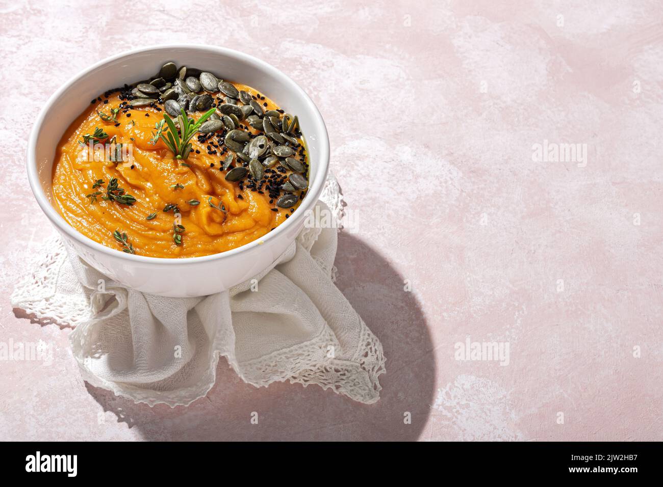 Au-dessus de l'appétissant purée de citrouille saine avec des graines et assaisonnement servi dans un bol en céramique blanche sur la table à la lumière du jour Banque D'Images