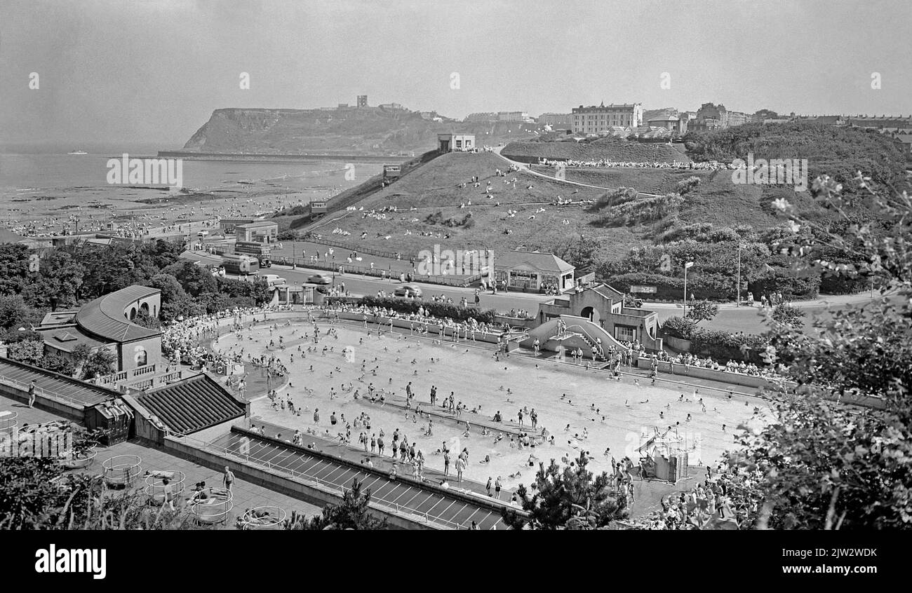 Une vue c. 1960 de la piscine de North Bay, Peasholm Gap, Scarborough, North Yorkshire, Angleterre, Royaume-Uni, avec North Bay au-delà. Le lido était une attraction populaire pour les nageurs de la station balnéaire. Auparavant un lac de navigation, il a été réaménagé en 1938, avec un hébergement pour les nageurs, les baigneurs de soleil et les sièges pour les spectateurs. Les bâtiments sont de style méditerranéen. Il a fermé en 2007 et a été démoli pour faire place à des appartements. Cette image est tirée d'un vieux négatif noir et blanc – une photographie vintage 1950s/60s. Banque D'Images